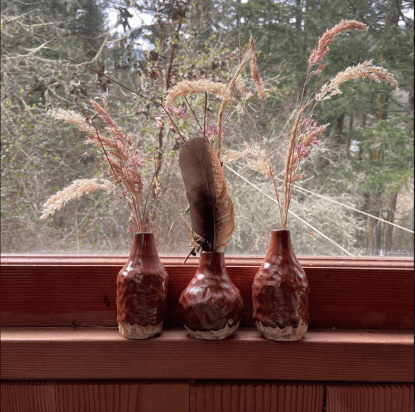 3 small red vases on a window ledge