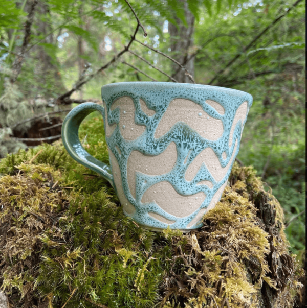 blue glazed mug perched on mossy log