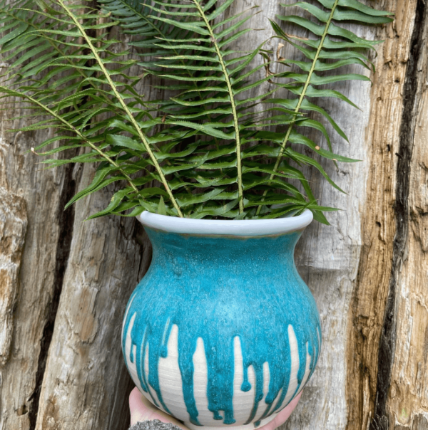 round blue vase with blue glaze, filled with fern fronds