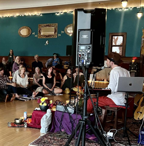 Rafe Pearlman seated at drum kit, performing for audience